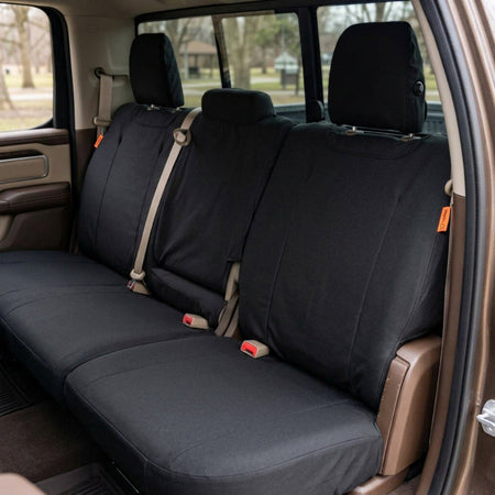 Three-piece black TigerTough Dodge Durango WD Cordura seat cover set installed on the rear bench of a vehicle interior, shown with the door open and outdoor scenery visible through the windows.