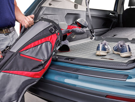 VW Tiguan with rear bumper protection protecting man loading golf bag into rear cargo area of car