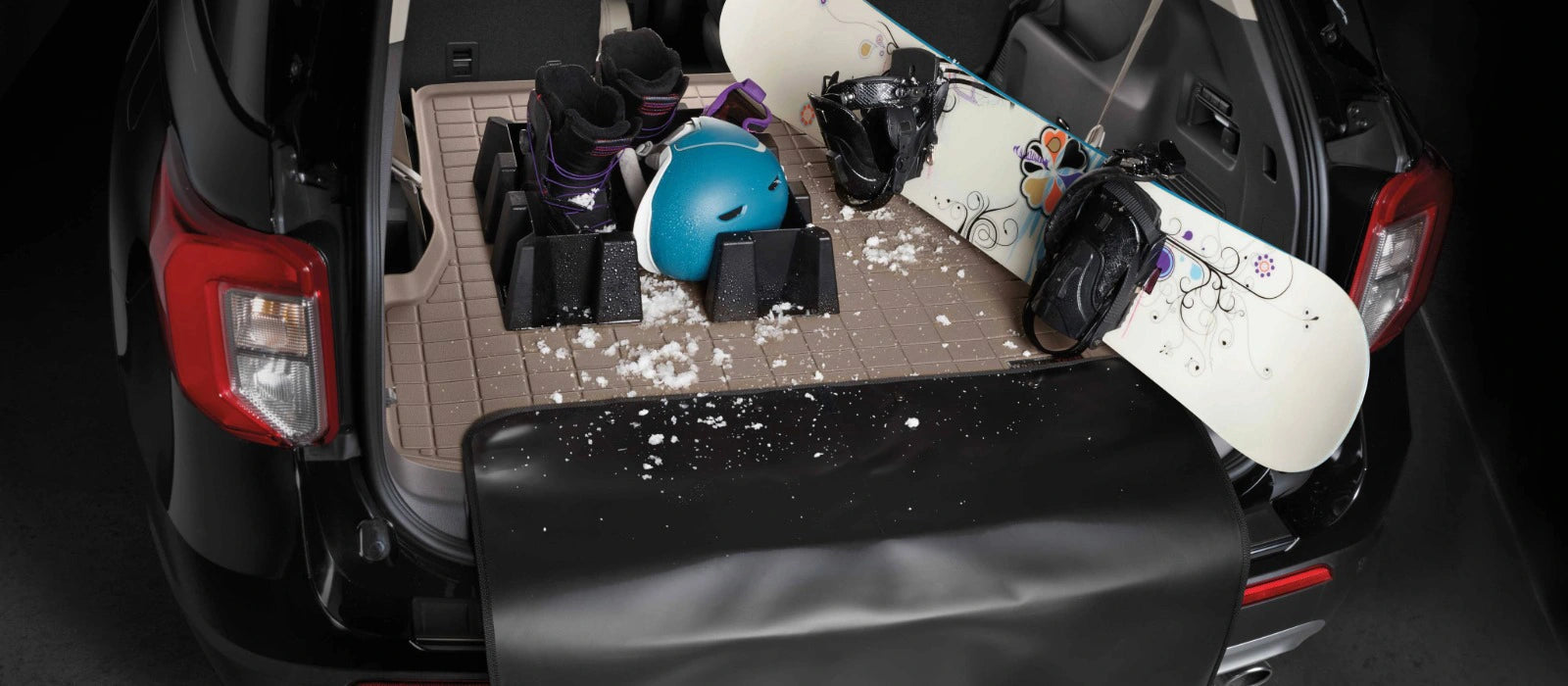 Car trunk with a snowboard and protective gear on a mat