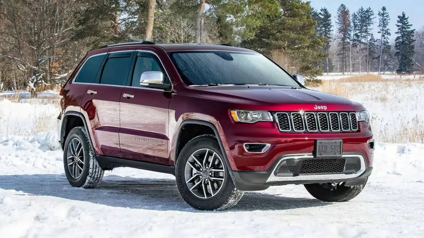 Red Jeep SUV parked on a snowy landscape with trees in the background