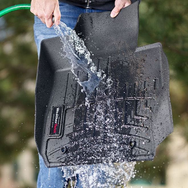 WeatherTech 1st row car liner being cleaned with a hose to show how waterproof the product is and how easy it is to clean